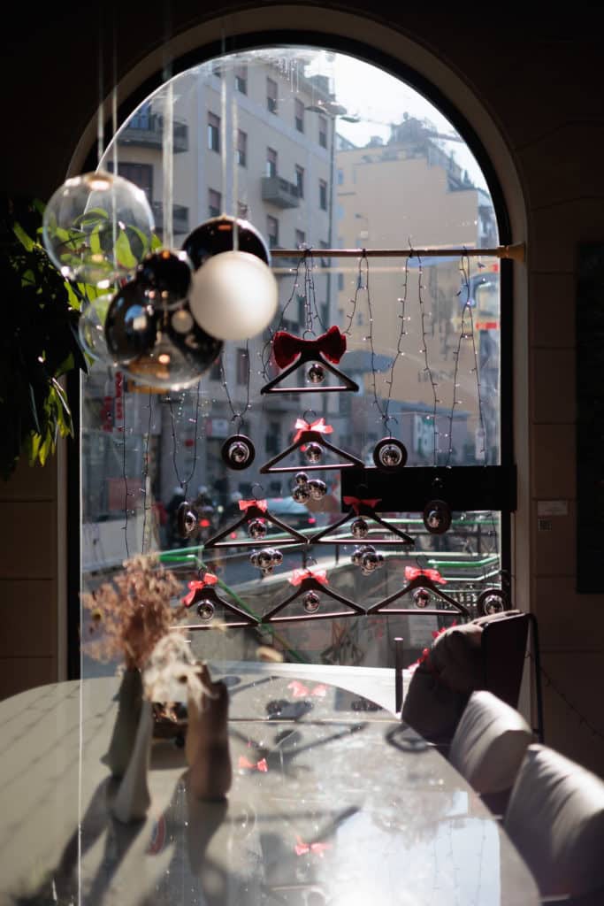Decorative Hanging Shoes And Ornaments In Front Of A Large Arched Window.