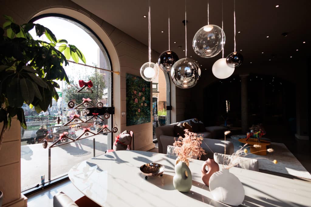 Modern Interior With Hanging Spherical Pendant Lights And Decorative Vases On A Marble Table.