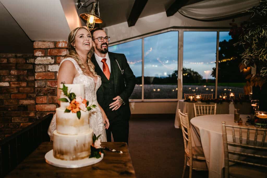 Wedding couple at Hyde Bank Farm, celebrating with a cake in a rustic venue.