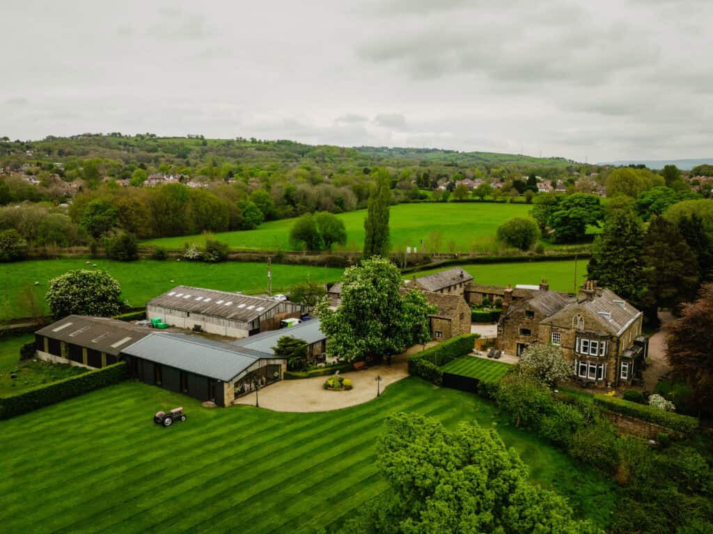 Aerial view of Hyde Bank Farm with lush green fields and historic farm buildings in the countryside.