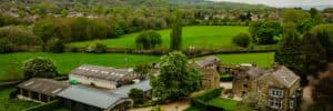 Aerial view of Hyde Bank Farm with lush green fields and historic farm buildings in the countryside.