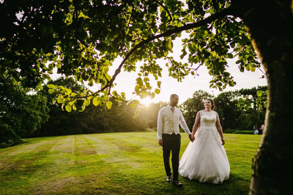 Wedding couple walking hand in hand in the scenic gardens of Hyde Bank Farm.