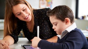 &nbsp;>thisisjustarandomplaceholder<Close up of young female teacher sitting at desk with a Down syn | Iberian Press®&nbsp;