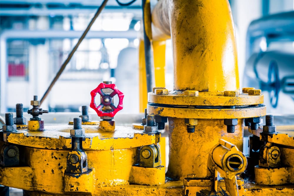 Close-up of yellow industrial valves with a red handwheel in a factory setting