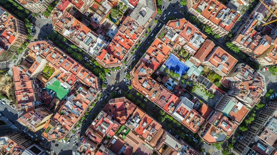 Aerial view of a dense urban neighborhood with red-tiled roofs and narrow streets.
