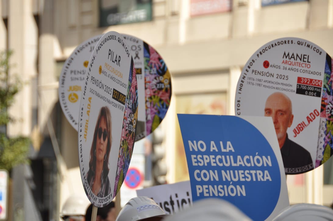 Blue protest sign reading 'NO A LA ESPECULACIÓN CON NUESTRA PENSIÓN' with circular campaign posters in the background, at a street demonstration.