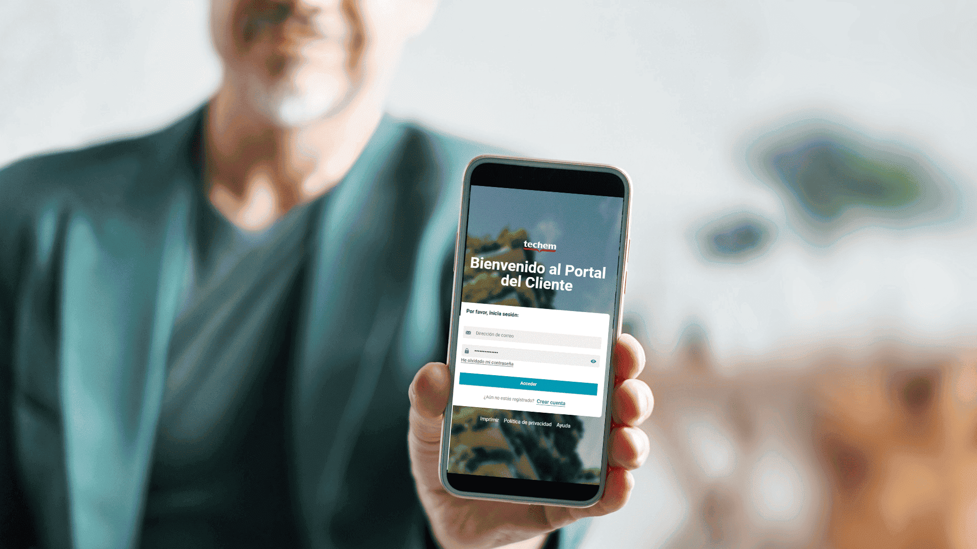 Teléfono en mano mostrando la pantalla del Portal del Cliente con el título Bienvenido al Portal del Cliente y campos de inicio de sesión (en español).