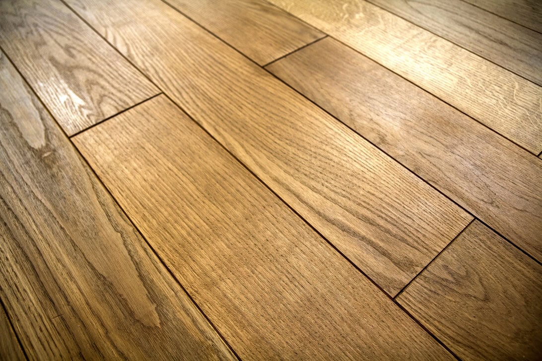 Wide view of warm brown hardwood floor planks with visible wood grain and seams between boards.