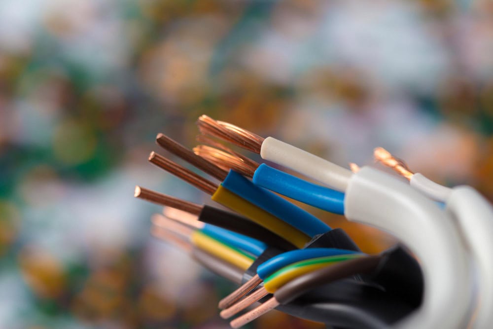 Close-up of multi-core electrical cables with exposed copper conductors and colored insulation (blue, yellow, green, black).