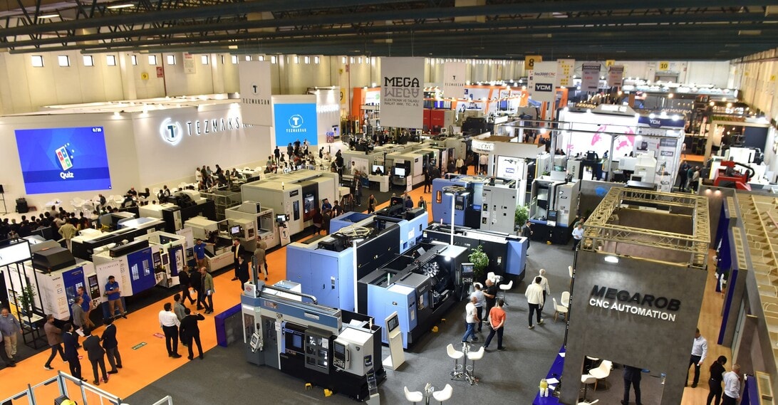 Aerial view of a large technology trade show with many industrial booths, displays, and attendees walking through aisles.
