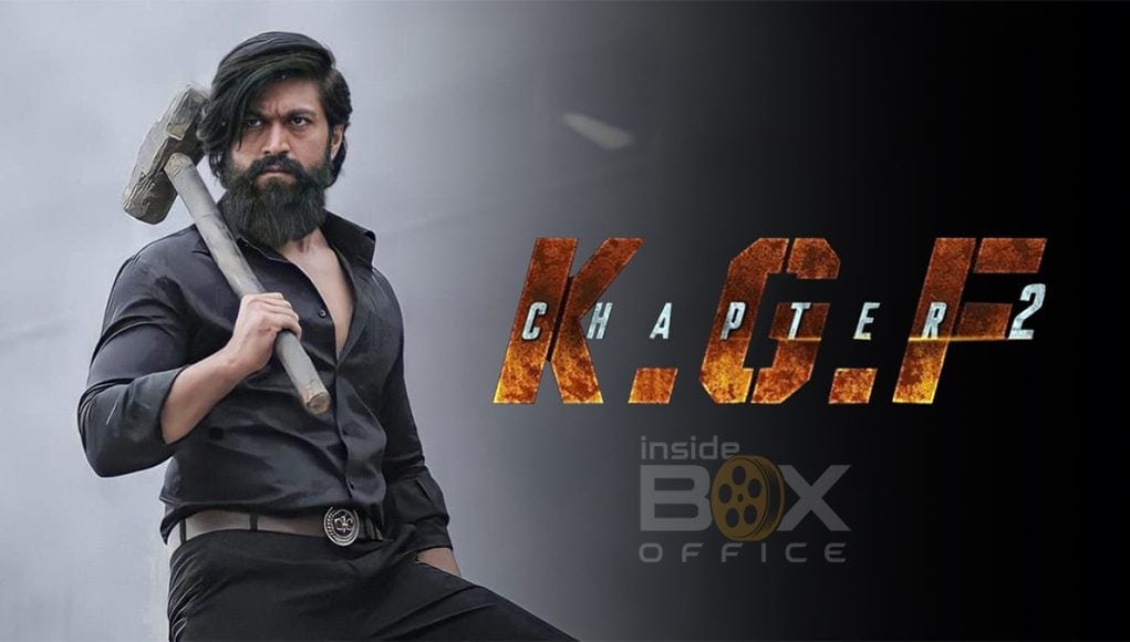 A formidable man with a beard and long hair, dressed in black, holding a hammer over his shoulder, promoting K.G.F Chapter 2, a popular Indian action film, featured on Inside Box Office.