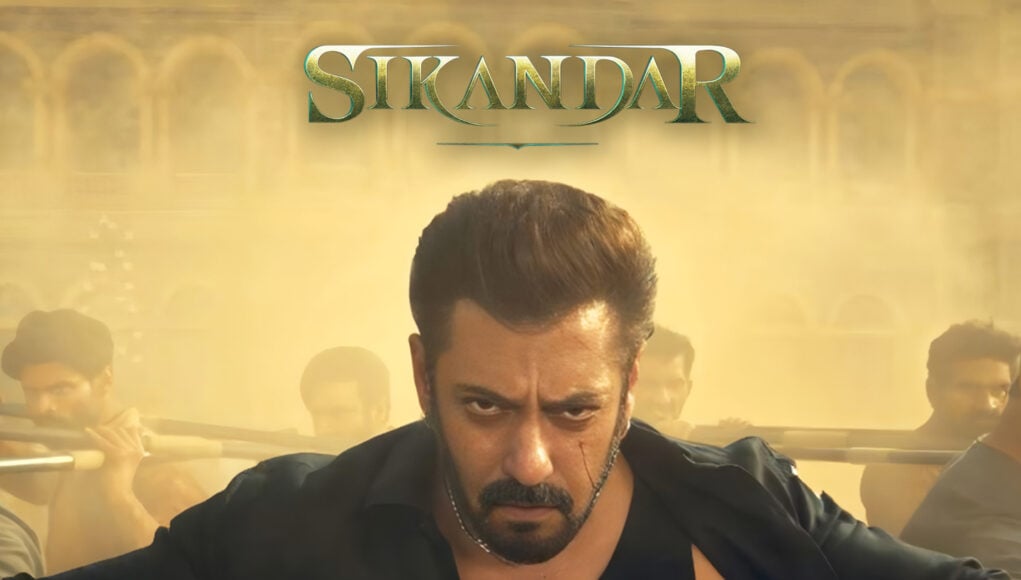 sikandar feature images 3 Intense action scene featuring a fierce male protagonist with a serious expression, surrounded by smoke and multiple characters, from the movie Sikandar, showcasing dramatic film visuals and fight sequences.