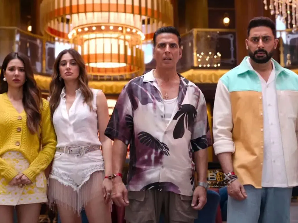 Stunned Group Of Four People In Brightly Colored Casual Clothes Inside A Lively Entertainment Venue, Capturing A Moment Of Surprise Or Shock.