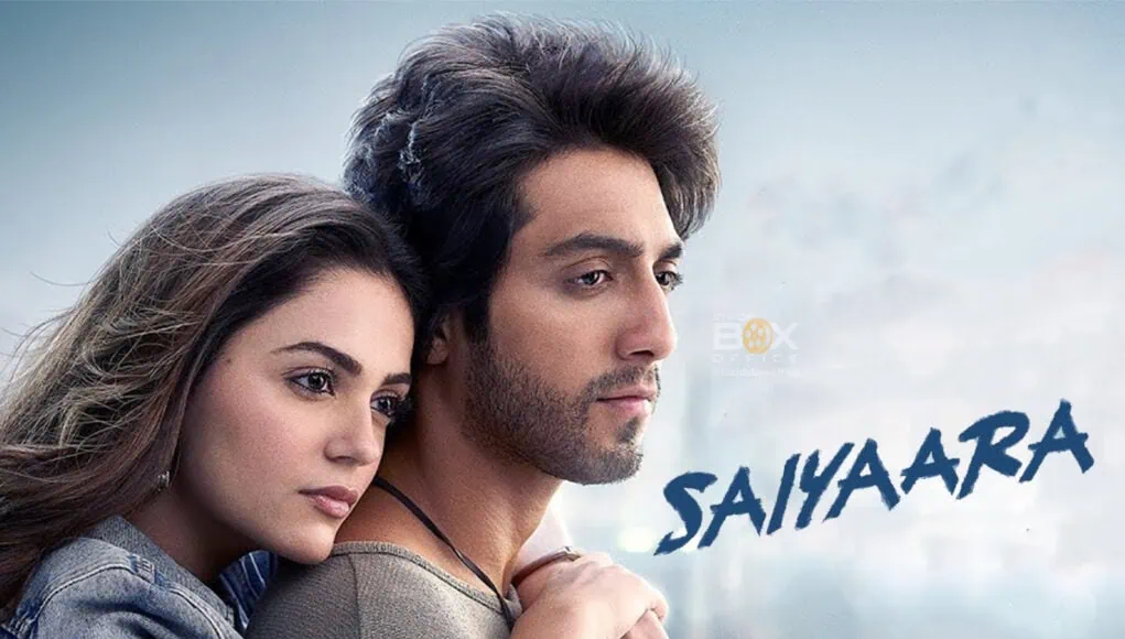 A young couple embracing, featuring Bollywood actors in a romantic scene for the movie Saiyara, with a cityscape background highlighting film industry themes.