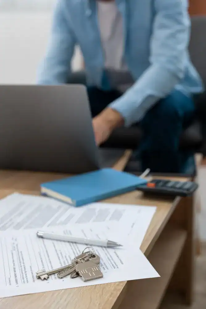 Business professional working at a desk with keys, documents, and a laptop.