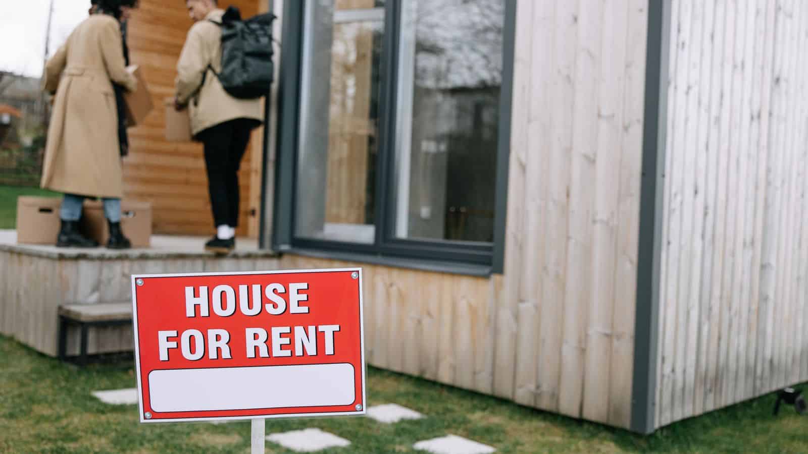 A house for rent sign in a front yard as new tenants move into a rental home