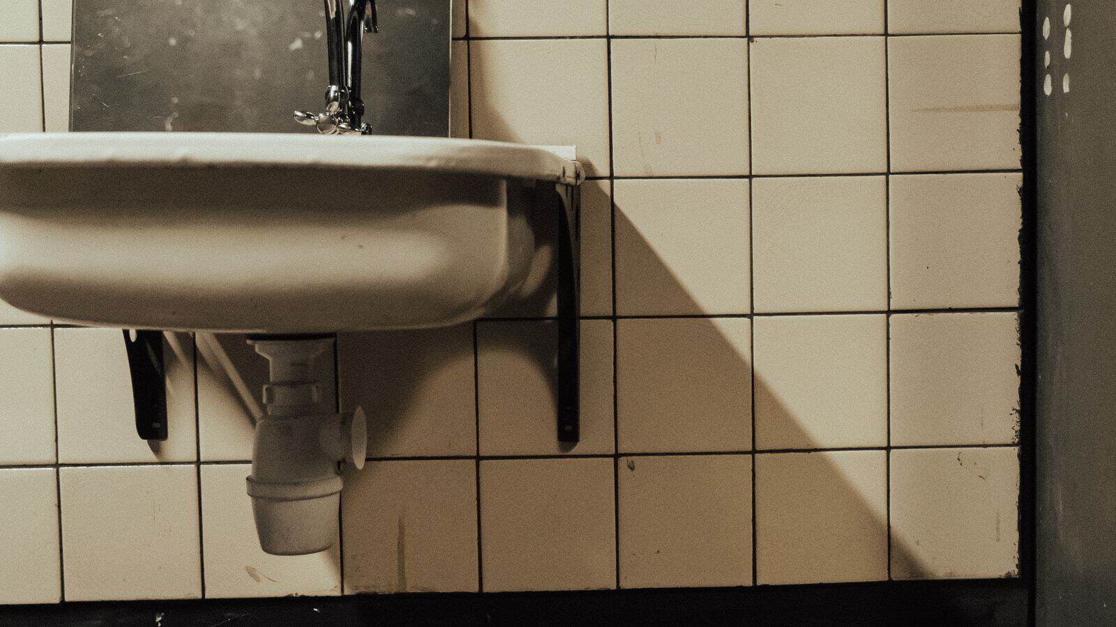 Exposed plumbing under a neglected apartment bathroom sink awaiting landlord repair in Las Vegas