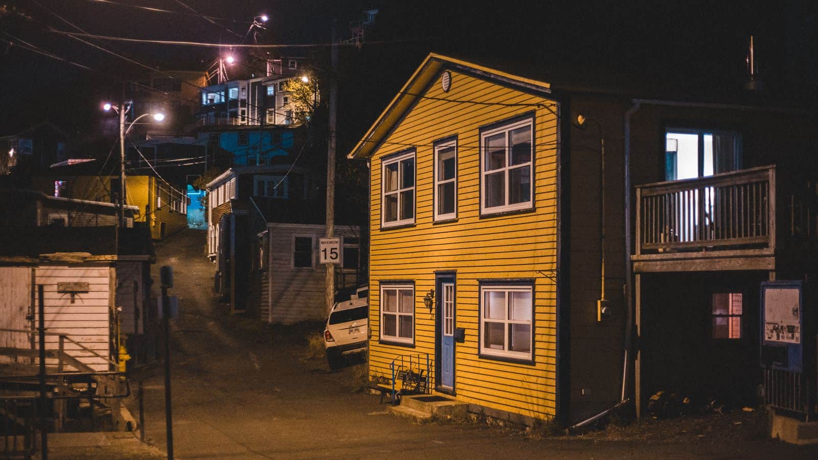 Quiet suburban street at night with porch lights glowing, the hours when rental emergencies tend to happen