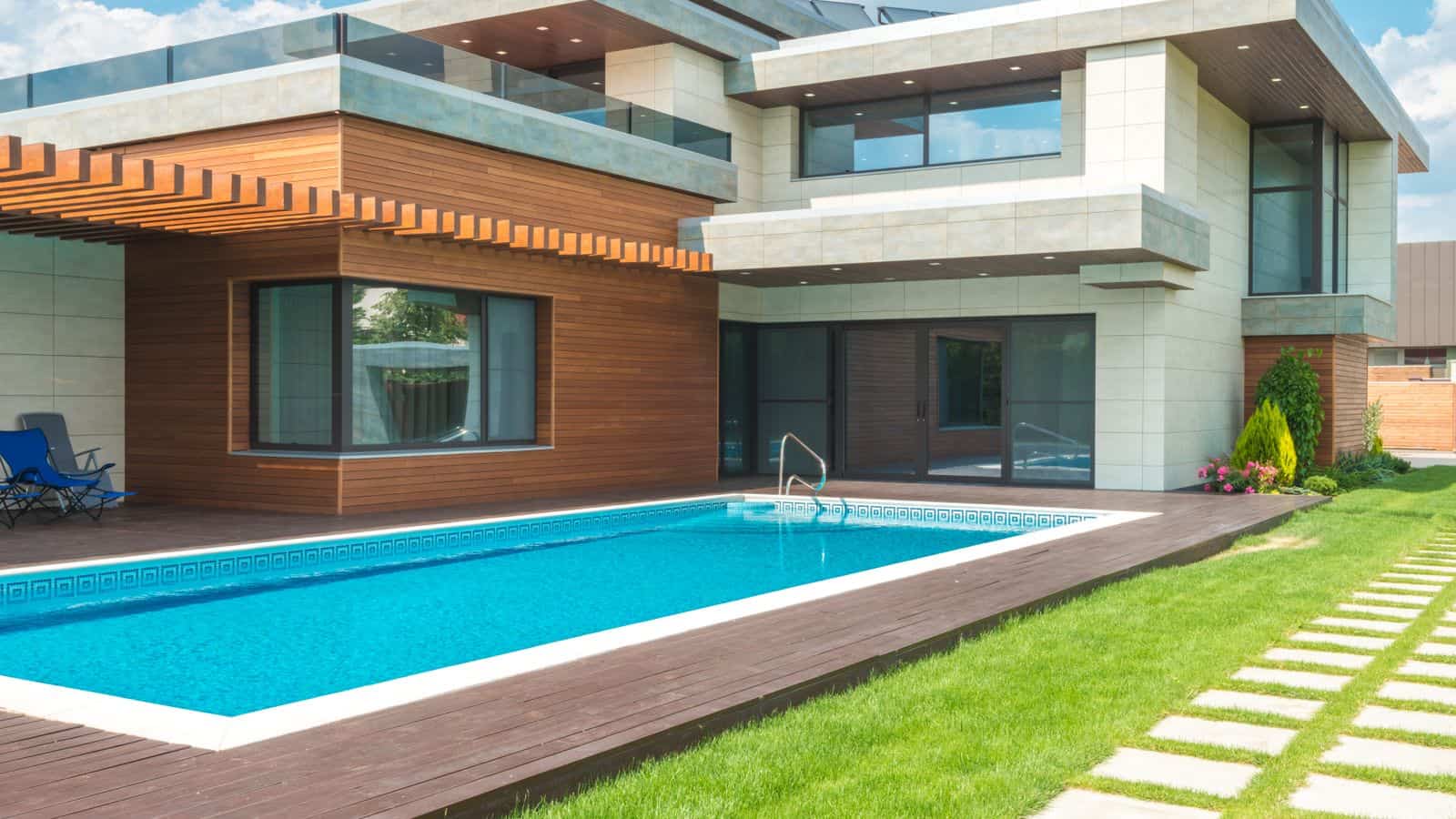 Modern two-story home with a backyard swimming pool and green lawn on a sunny day