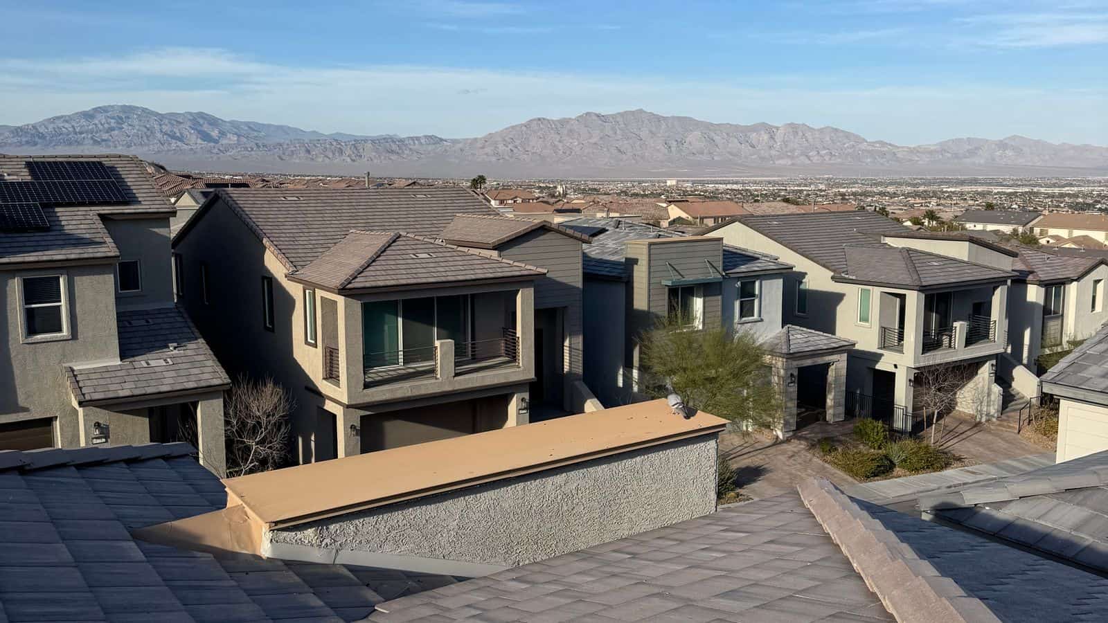 Suburban single family homes with tile roofs under a clear desert sky in a Las Vegas master planned community