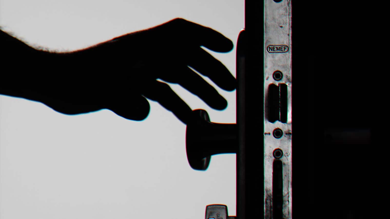 Hand holding keys in the lock of a front door at dusk