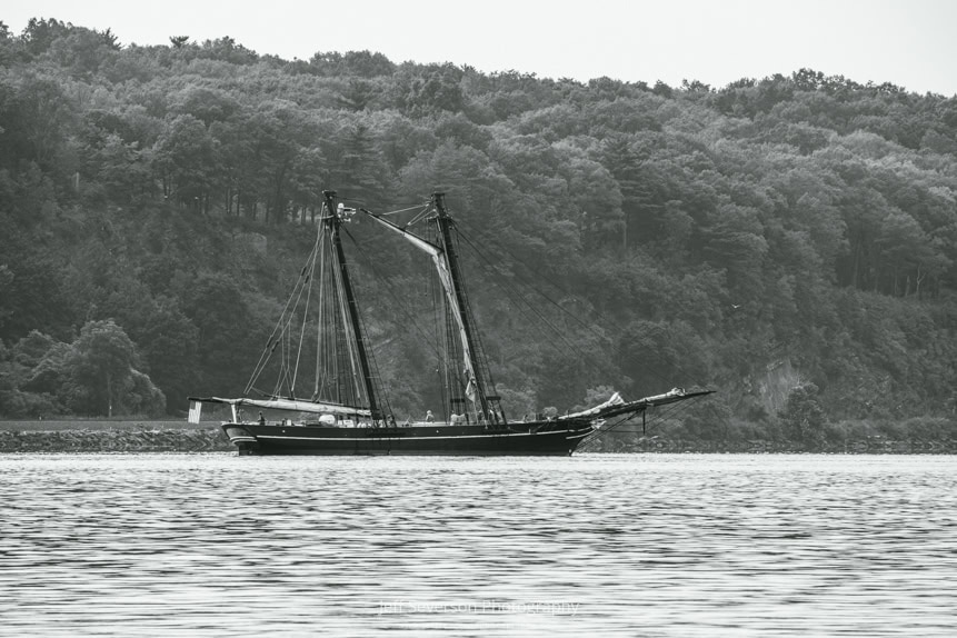A black and white photo of The Amistad, a replica of a 19th century schooner, on the Hudson River as it waits to enter the Rondout Creek.