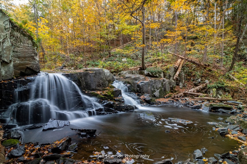 A long exposure photography of Middle Falls on Black Creek with fall foliage surrounding it.