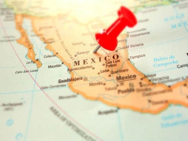 Closeup of a map with a red pin stuck in Mexico