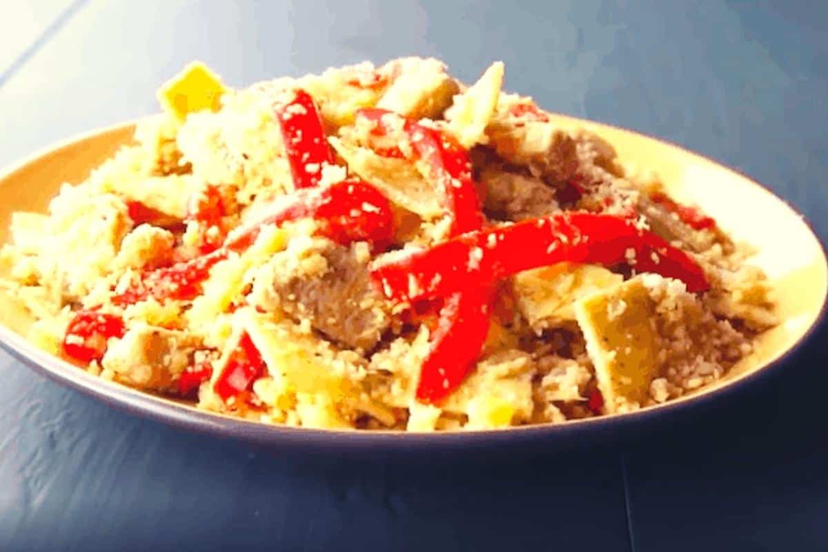 A plate of cauliflower rice mixed with juicy chicken, red peppers, and a light sprinkling of grated cheese sits on a blue table—perfect inspiration for your next Slimming World chicken recipes.