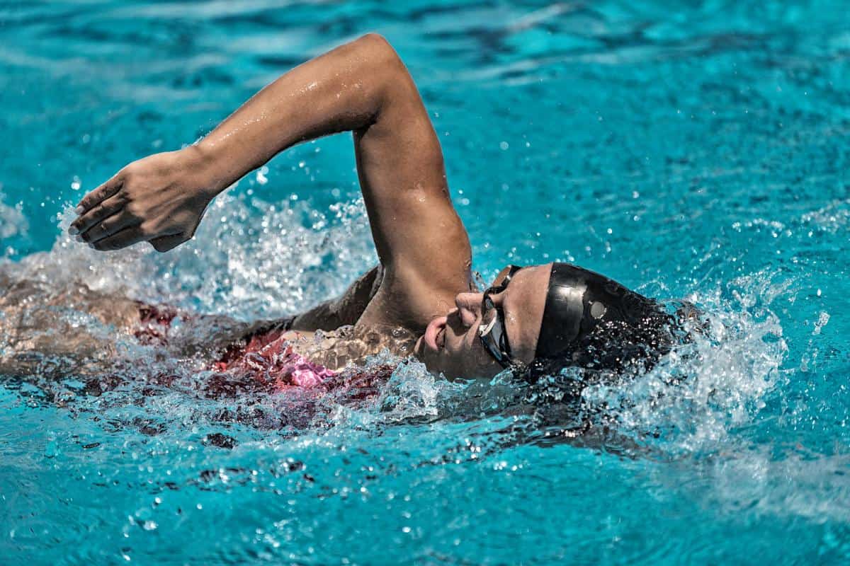 A lady swimming with goggles and a swimming cap.