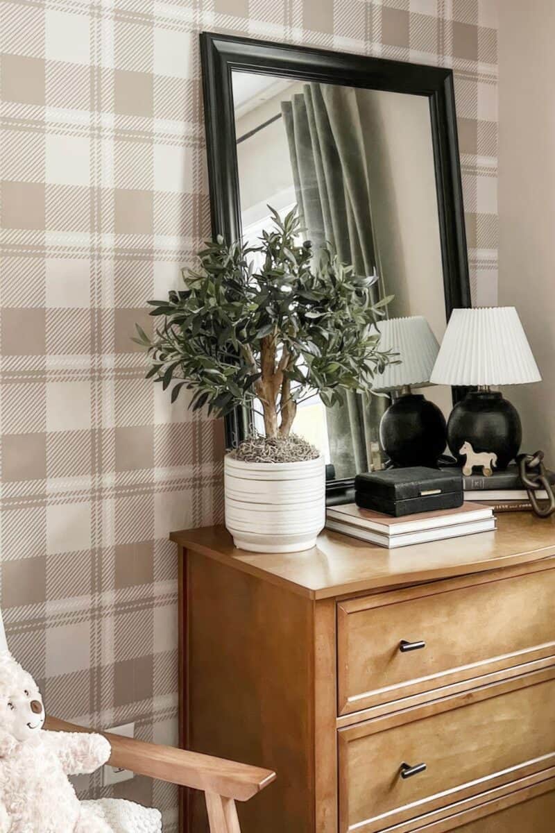 A dressing table with drawers in a bedroom in front of checked wallpaper.