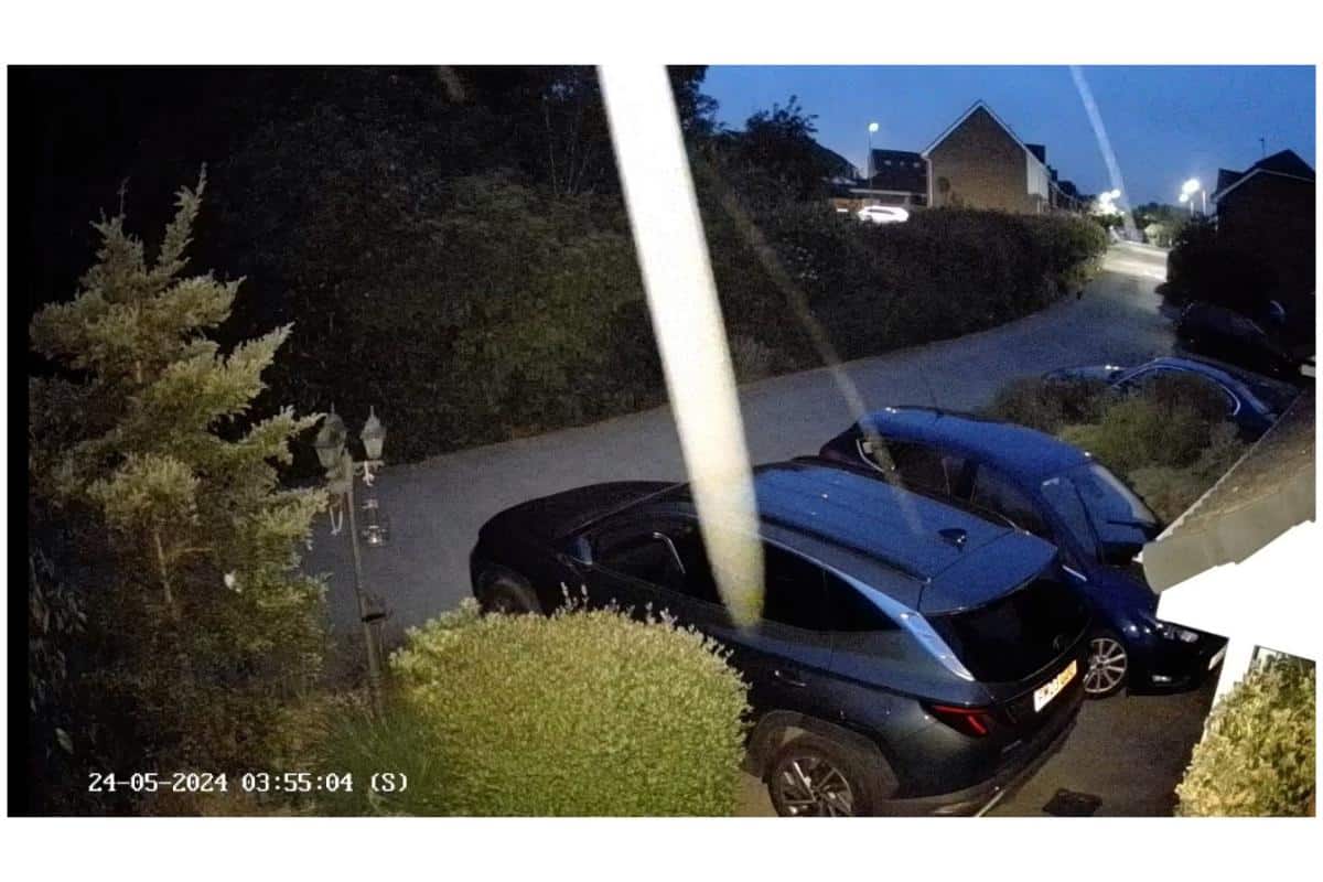Nighttime security camera footage from an Ezviz H8 Pro captures a driveway with two parked cars. A bright white streak appears across the image, lending an air of mystery. The timestamp reads "24-05-2024 03:55:04 (S).