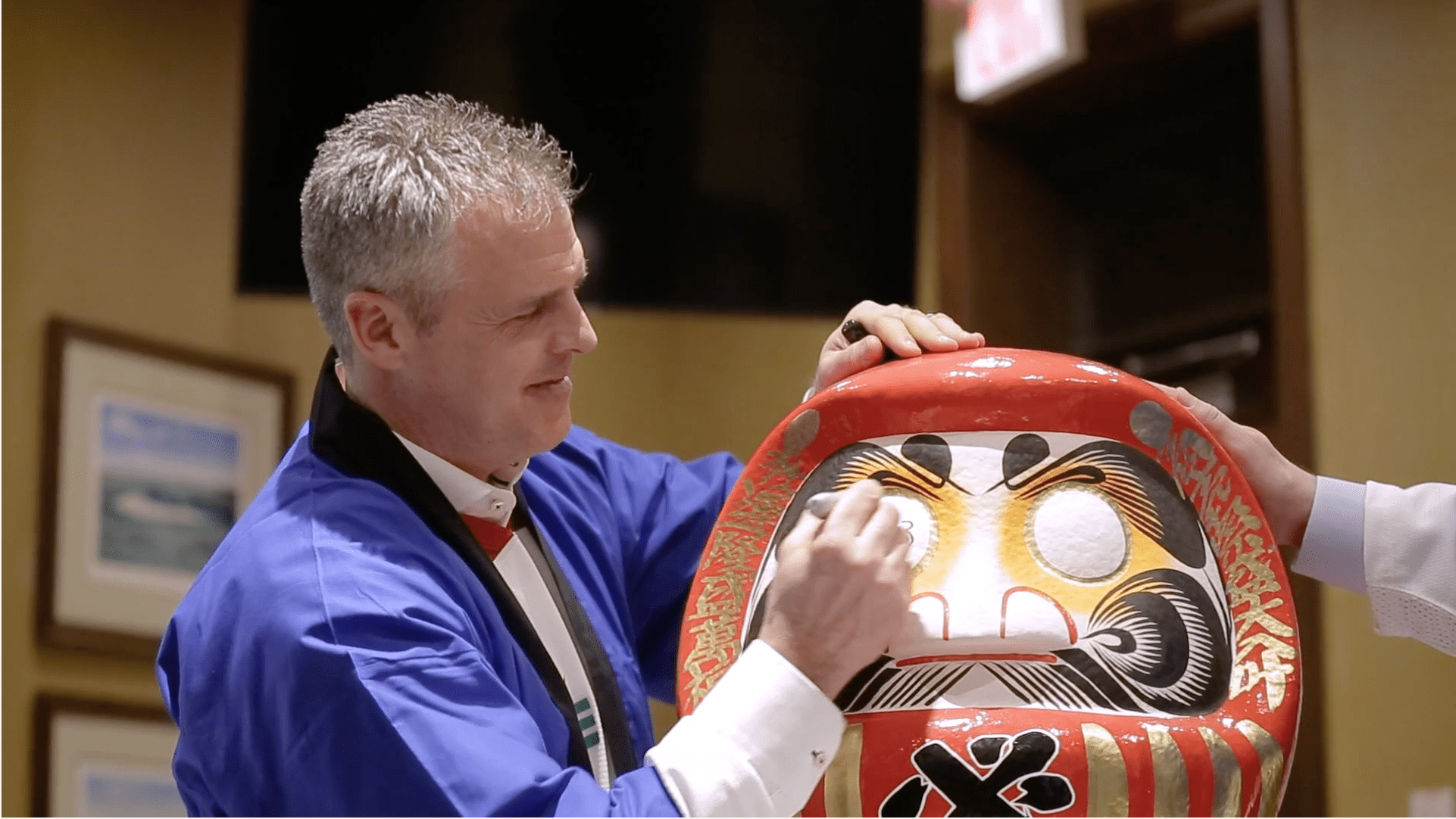 man draws on daruma doll eye