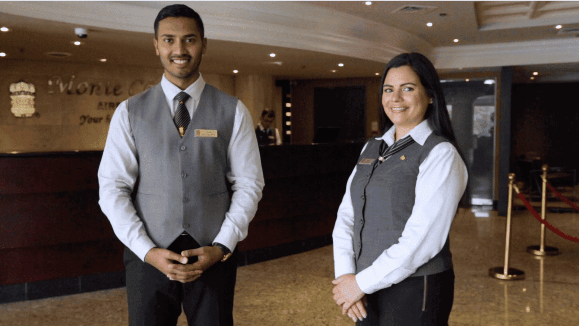 two hotel employees stand in front of desk