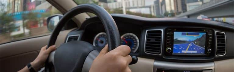 Driving a car with GPS navigation system on the dashboard.