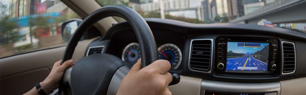 Driving a car with GPS navigation system on the dashboard.