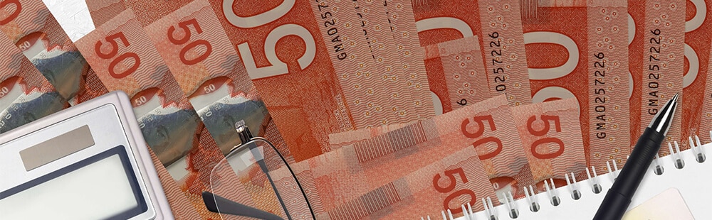 Financial planning with Canadian $50 bills, calculator, glasses, and notebook.