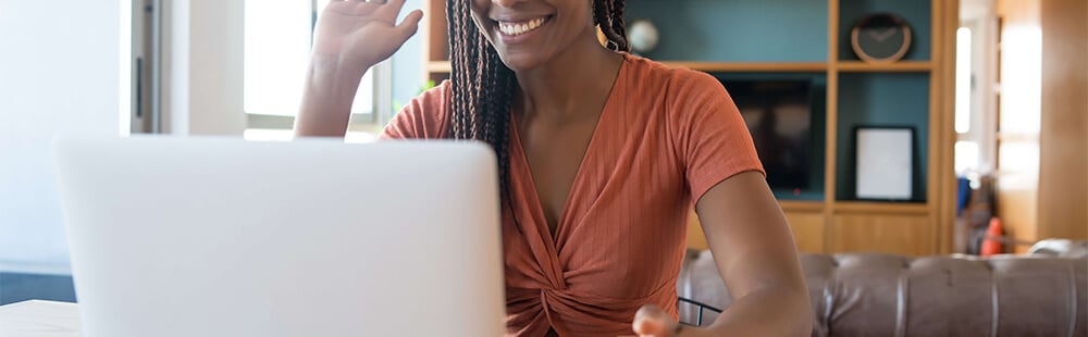 Woman smiling while using a laptop in a modern, well-lit living space.