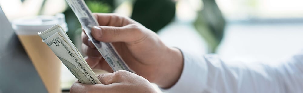 Person holding cash and credit card during a financial transaction.