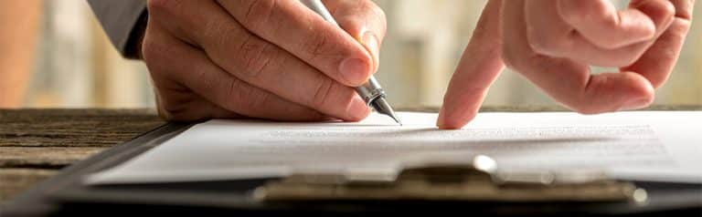 Business professional signing important paperwork with a pen.