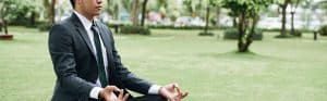 Meditating person in a park, practicing mindfulness outdoors.