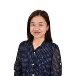 Smiling woman in navy polka dot blouse, standing outdoors with natural light.