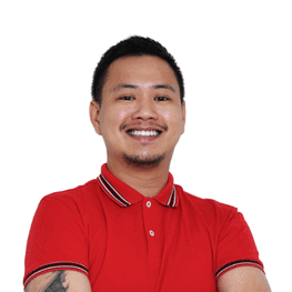 Smiling man in red polo shirt with crossed arms, outdoors, cheerful expression.