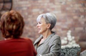 Elderly women engaging in friendly conversation in a warm, inviting space.