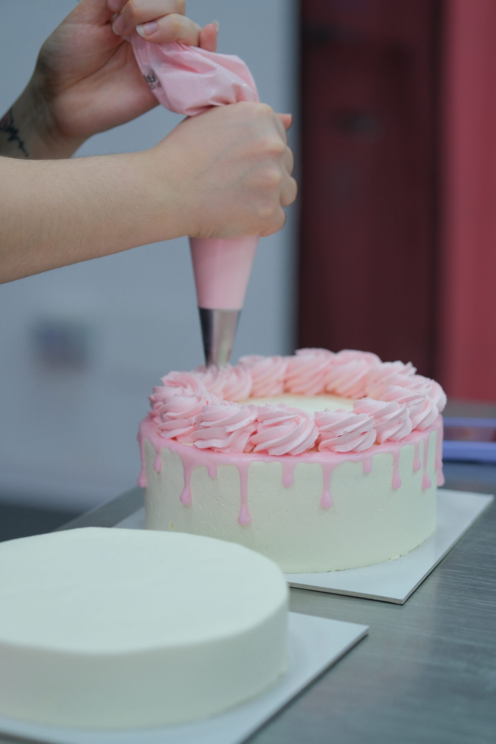 Decorazione torta con crema rosa e sac à poche, pasticceria artigianale LallabyCakes.