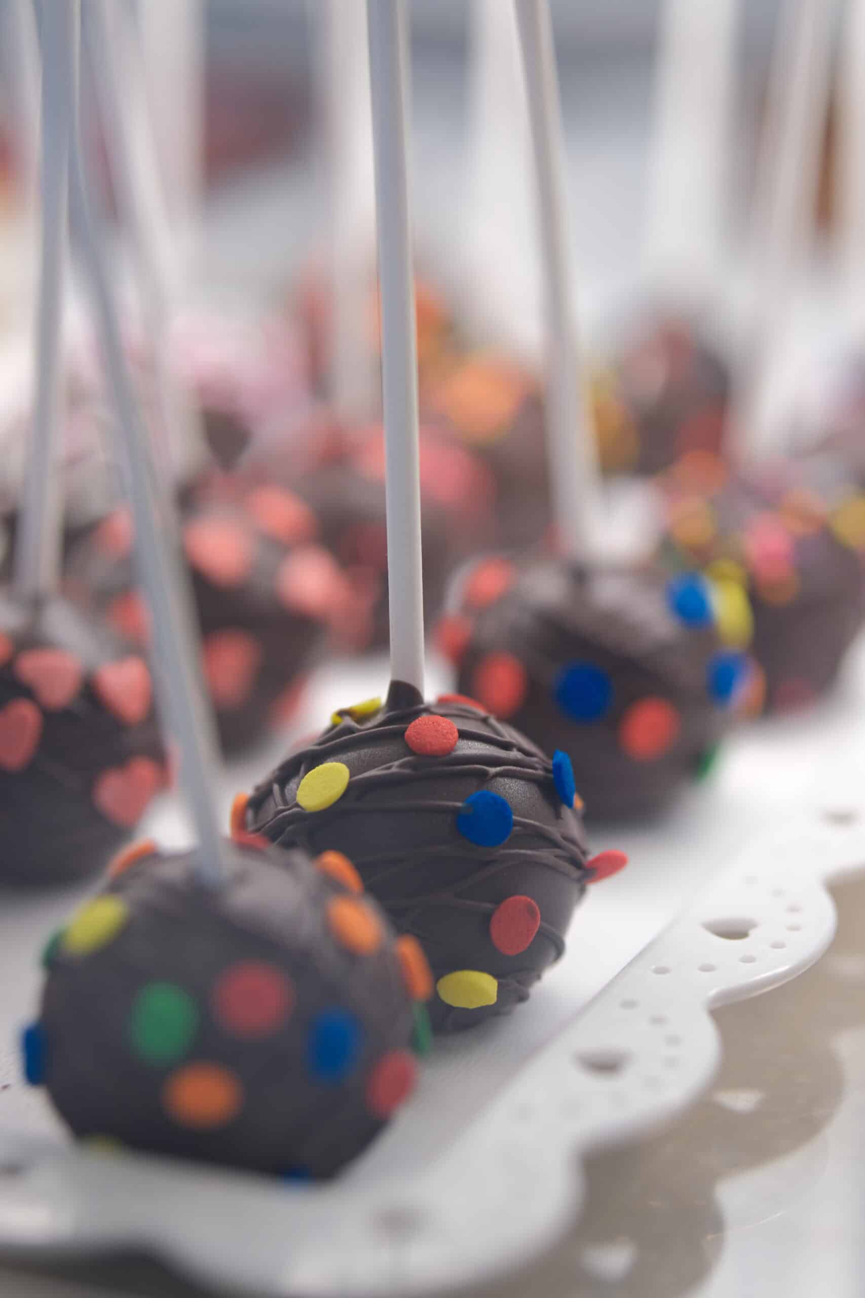 Cake pops al cioccolato decorati con confetti multicolori, perfetti come dolce festa.