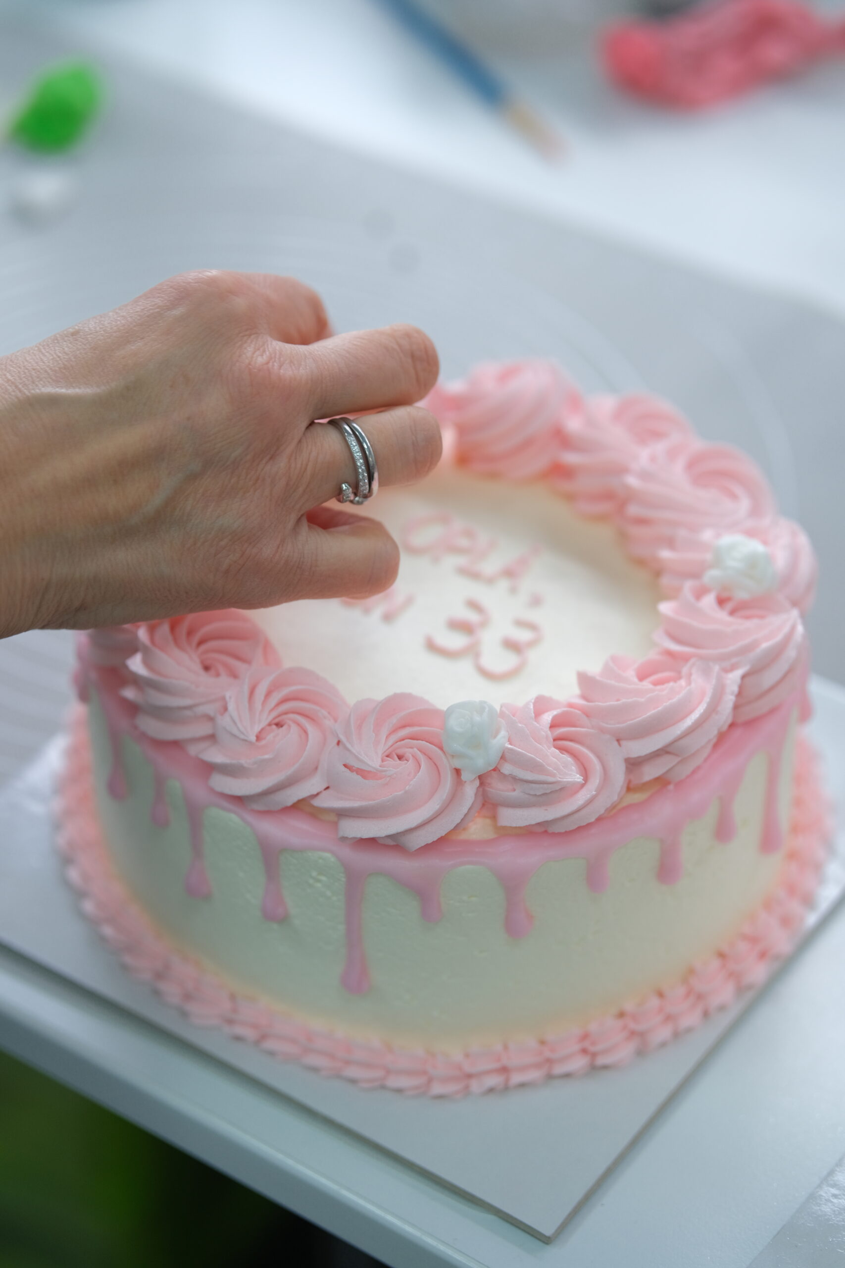 Torta di compleanno rosa con decorazioni di panna e scritta Om.