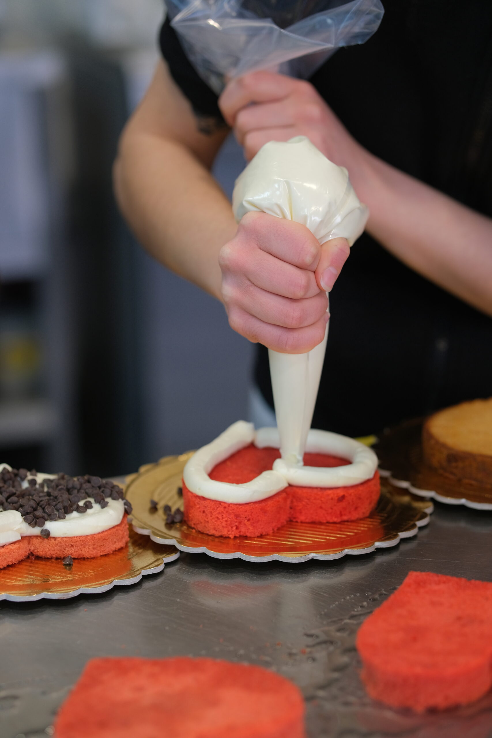Decorazione di una torta con crema bianca e decorazioni rosse, realizzata con sac à poche in una pas.