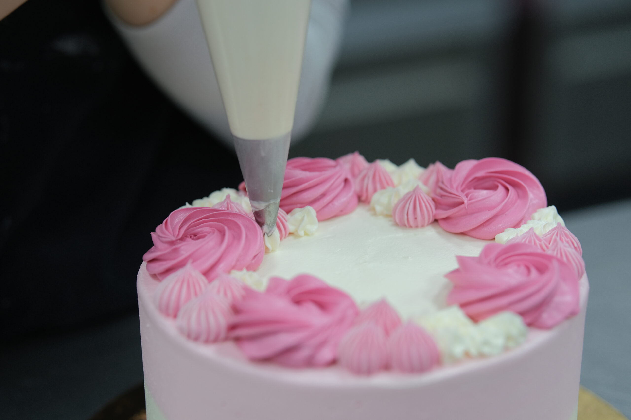 Torta decorata con glassa rosa e bianca, perfetta per occasioni speciali, creata dalla pasticceria L.