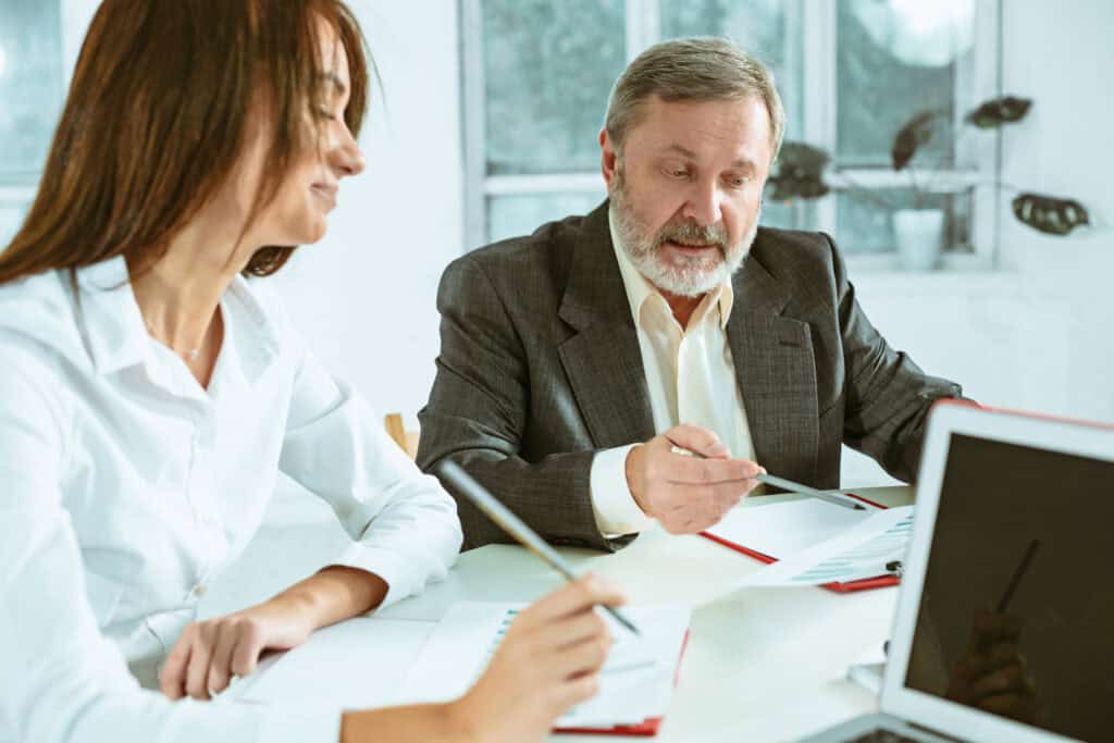 Abogados en una reunión de negocios, revisando documentos y utilizando un portátil, representando la implementación del mejor software jurídico para abogados en 2025